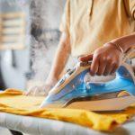 Close up of unrecognizable young woman ironing clothes at home, simple lifestyle and household chores concept, copy space